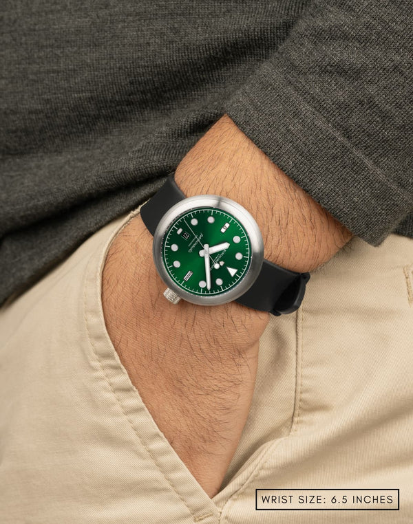 Man wearing Agumbe wristwatch with hand in pocket, featuring the deep green dial color with sunburst pattern and diver-style applied indices.