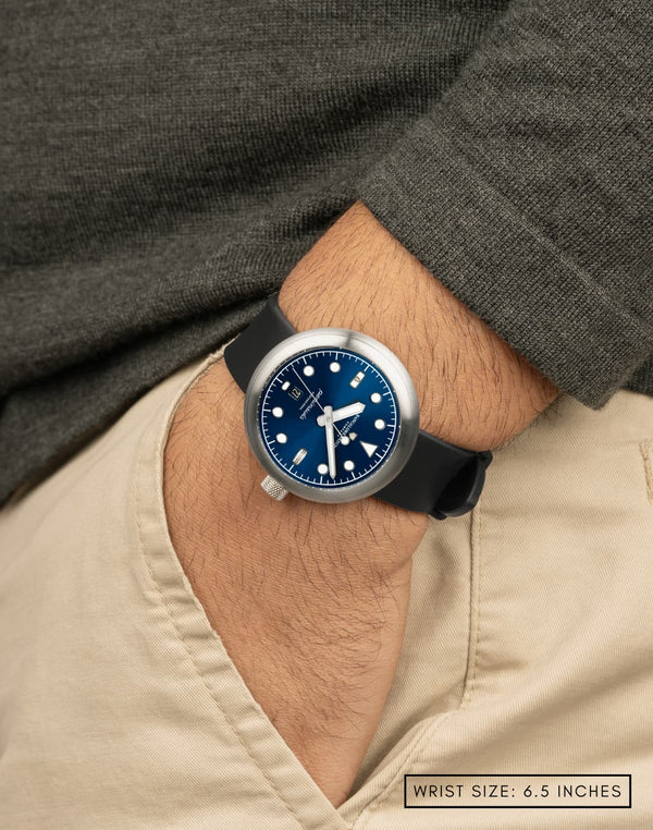 Man wearing Laccadive wristwatch with hand in pocket, featuring the deep blue dial color with sunburst pattern and diver-style applied indices.