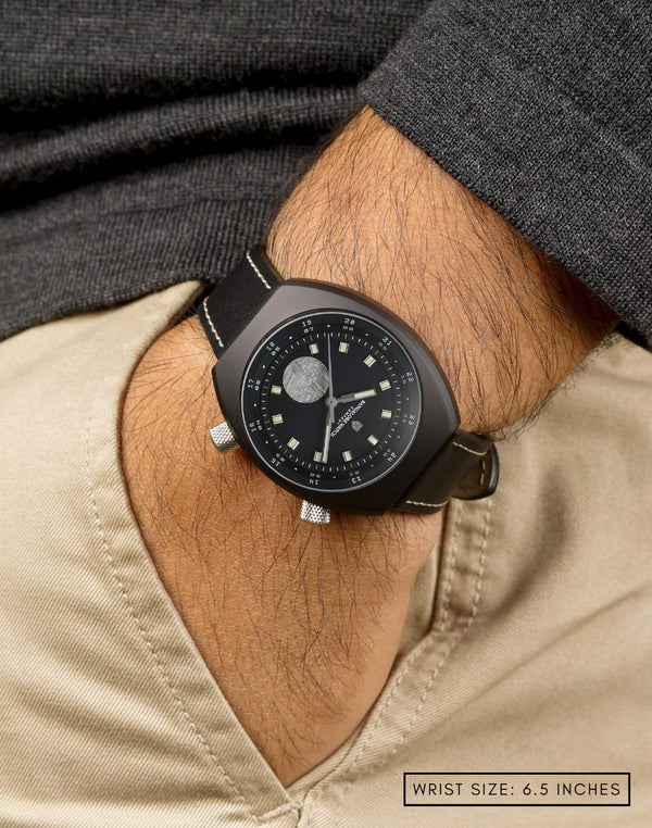 Man wearing Manzinus II watch, hand in pocket, highlighting its 9mm Muonionalusta meteorite disc at 6H.